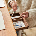 Walnut under-desk drawer mounted beneath a desk holding stationery