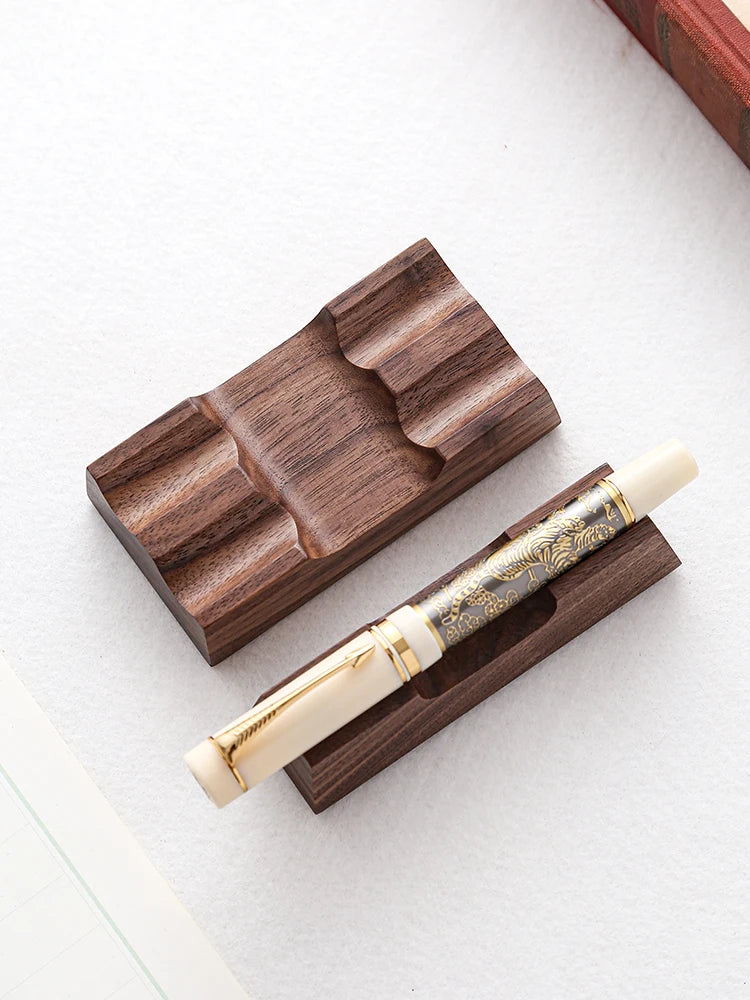 Walnut pen rest and organizer holding a fountain pen horizontally