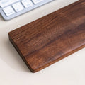 Walnut palm rest positioned beside a mouse on a desk pad