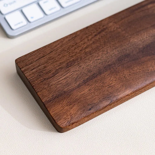 Walnut palm rest positioned beside a mouse on a desk pad