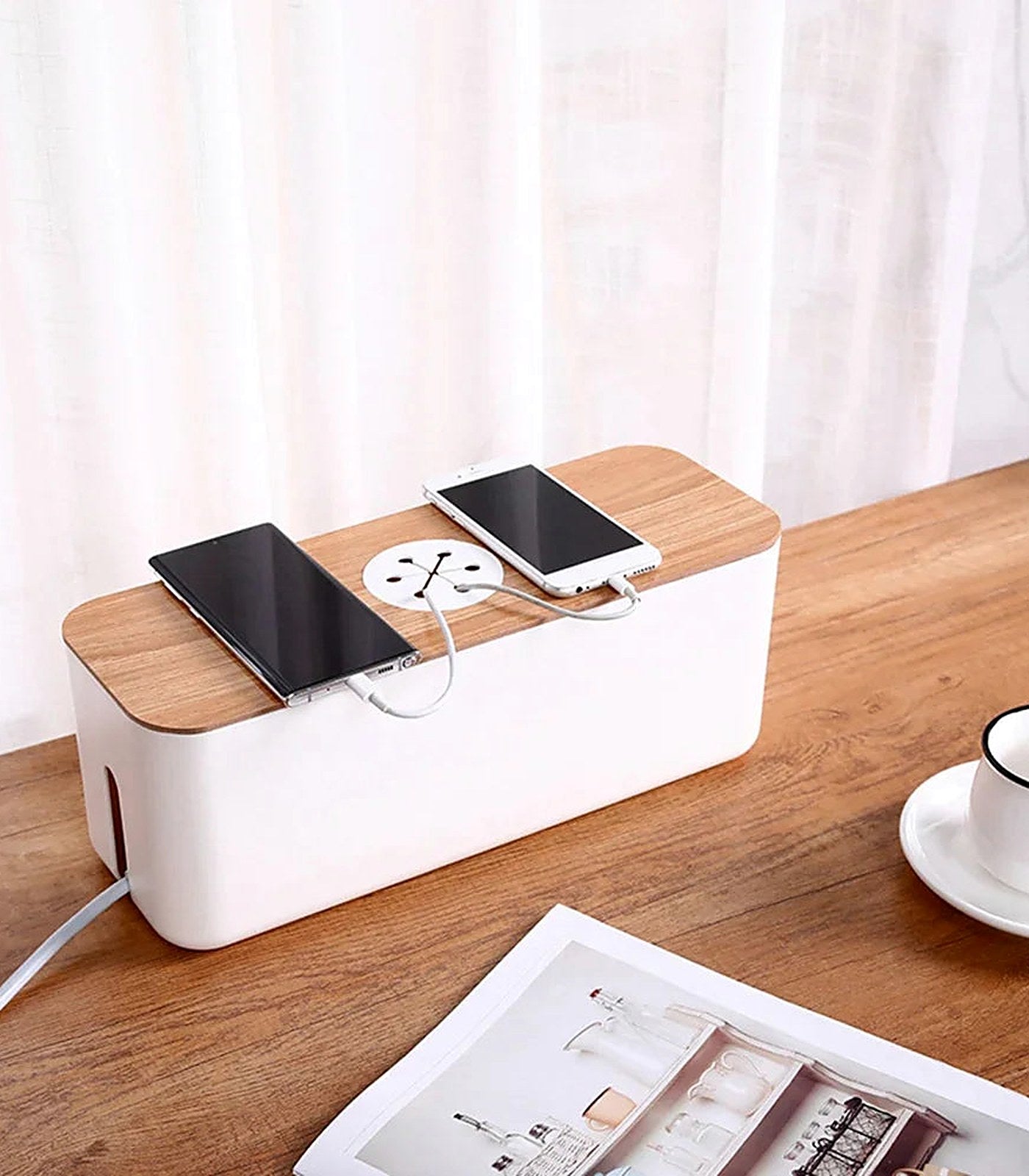 A cable management box on a desk with two phones charging on its lid